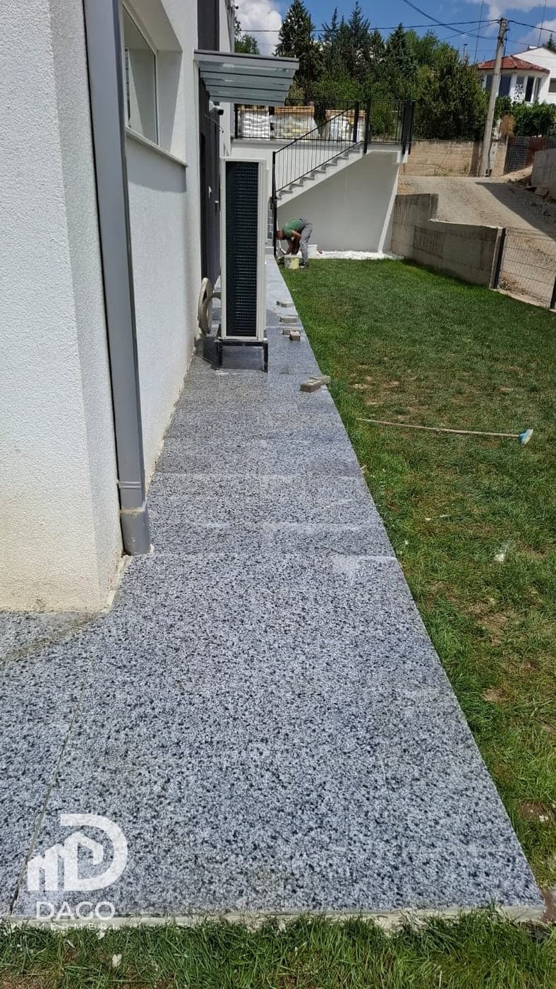 Polished grey granite tile path along a house